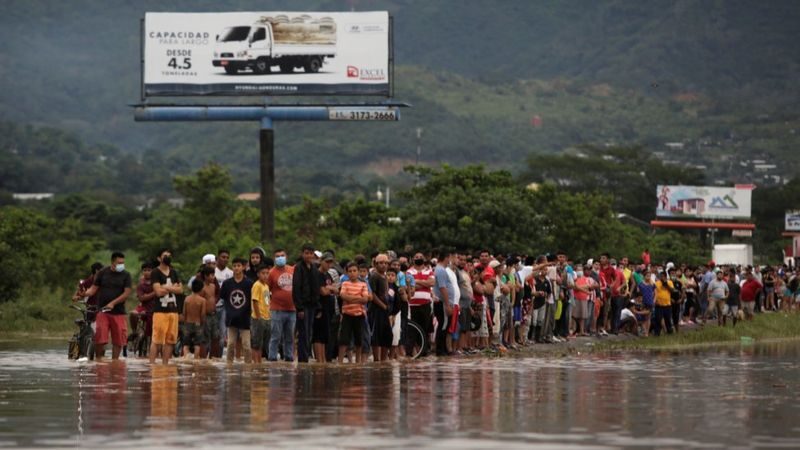 Hondurans wait on a flooded street after Storm Eta passed through the region