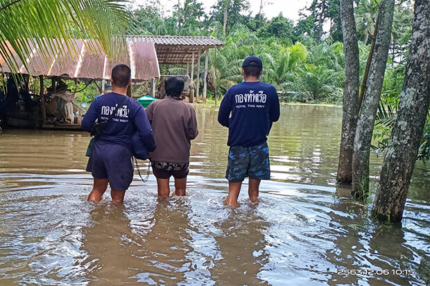 Navy soldiers accompany a villager through knee-deep floodwater, as they arrive to help people in Sathing Phra district of Songkhla on Monday.