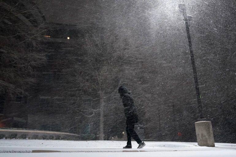 A woman walks through falling snow in San Antonio, Texas, the United States on Sunday, February 14, 2021