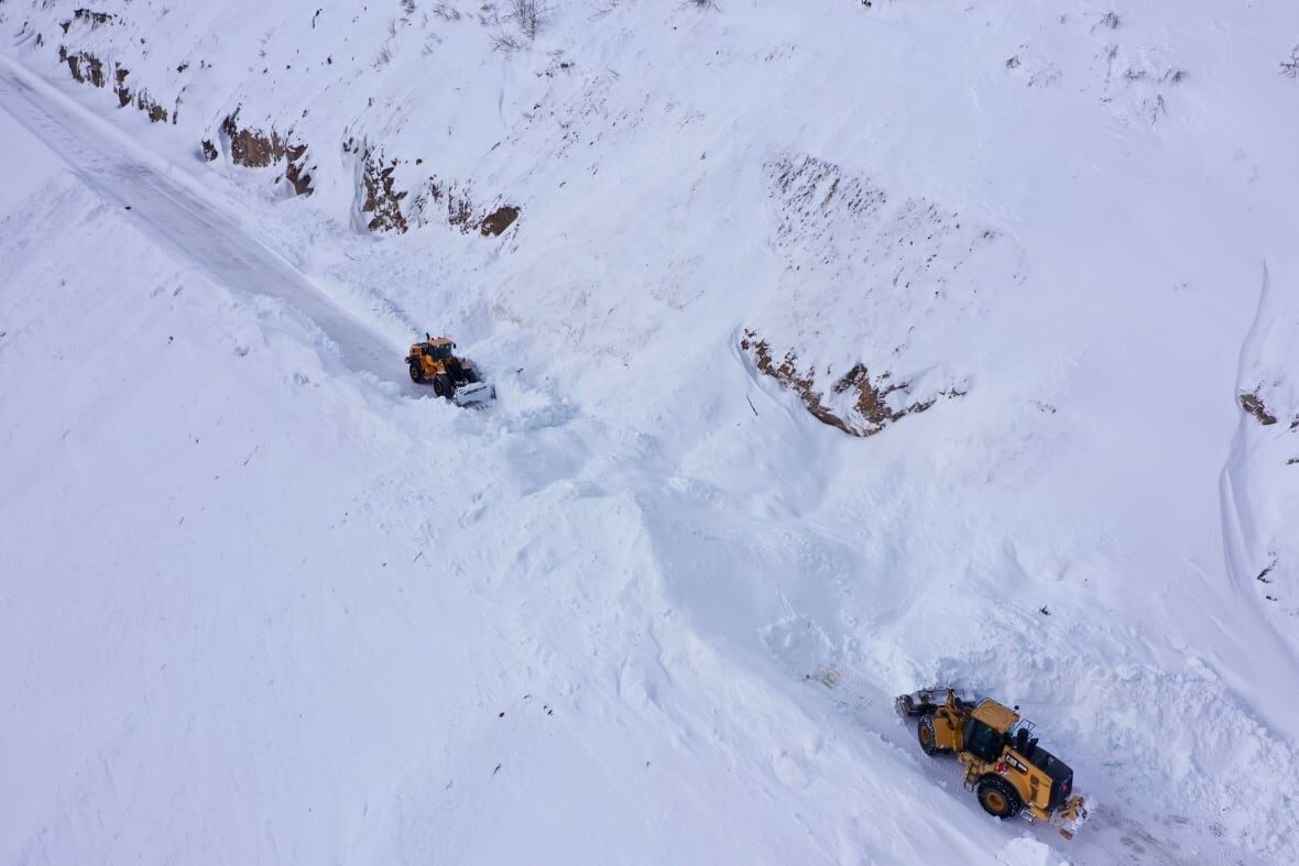 Workers remove snow piled up along the South Klondike Highway on March 2, 2021