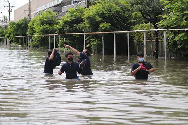 Workers wade through floodwater on Sunday after Saturday night downpours submerged the Bangpoo Industrial Estate in Muang district of Samut Prakan.