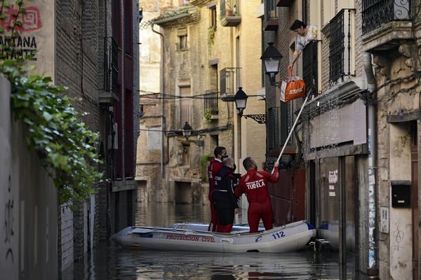 A rescue team help a woman in her home in a flooded area near the Ebro River in Tudela, northern Spain, Sunday, Dec. 12, 2021.