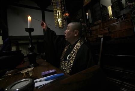 Koyu Abe, a Zen priest, lights a candle