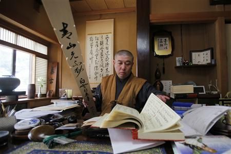 Koyu Abe, a Zen priest, looks through a book