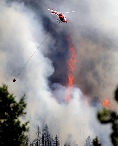 A firefighting helicopter flies above the fire near Bison Drive on Tuesday west of Boulder.