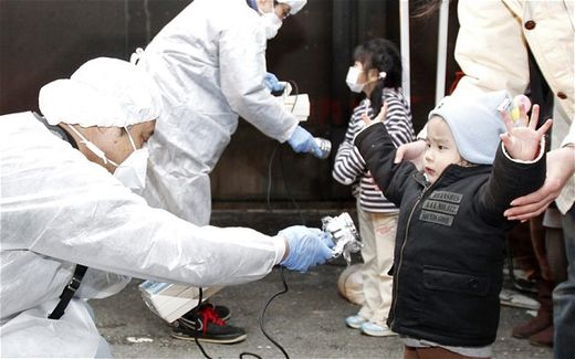 Click to enlarge Officials in protective gear check for signs of radiation on children