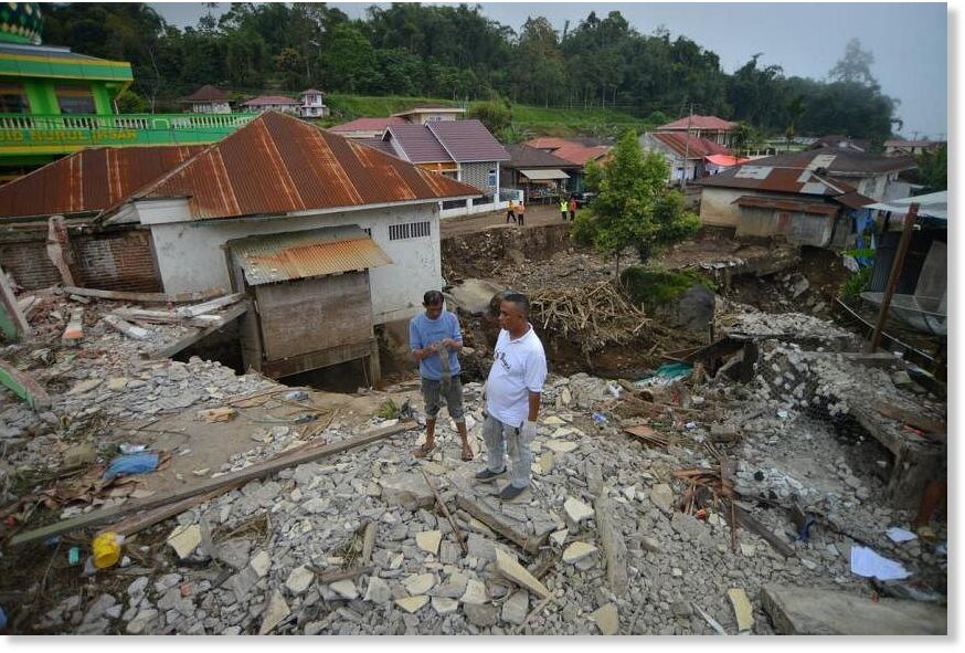 Men standing near a damaged house in Tanah Datar in the West Sumatra province