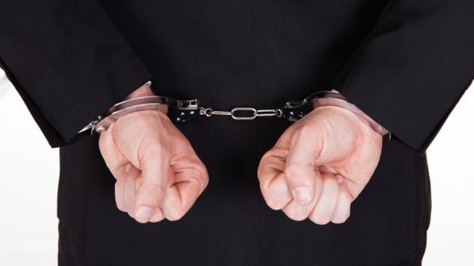 Click to enlarge man in black suit wearing handcuffs