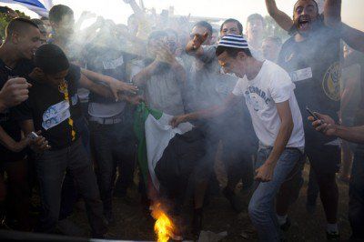 Click to enlarge Israelis burn a Palestinian flag