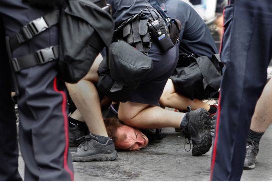 A police officer kneels on the face of Geoffrey Bercarich - G20 Toronto, Canada 