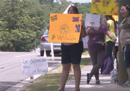 Click to enlarge Protesters gather outside dental office
