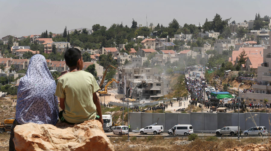 Palestinians watch Israeli heavy machinery demolishing apartment blocks