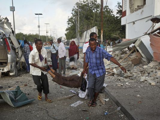Click to enlarge Somali men carry wounded after hotel attack