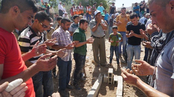 Mourners pray over the grave of Sa’ad Dawabshe