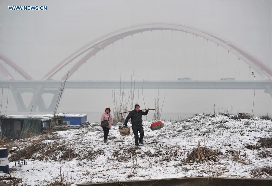 Citizens walk on the snow-covered bank of the Xiangjiang River in Changsha, capital of central China's Hunan Province, Feb. 1, 2016