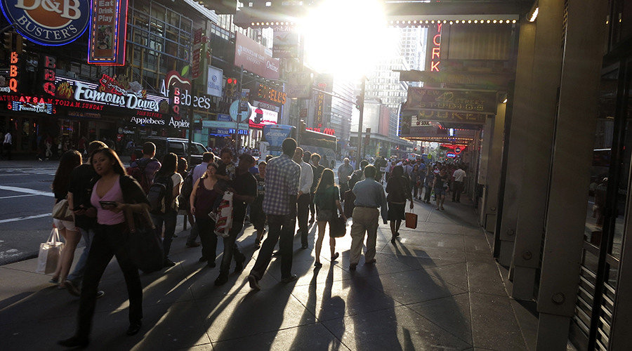 Click to enlarge People walk along 42nd Street as the sun sets on Times Square in New York