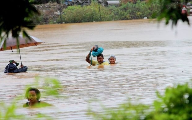 Residents of Korociri cross the flooded Nadi Back Road 