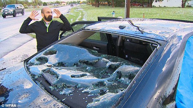 Nightmare: Adrian Correa pictured with his semi-collapsed car. His eight-month-old girl was in the car when hail sent glass flying into the back seat, leaving her with scratches, as they drove near Wylie, he told WFAA