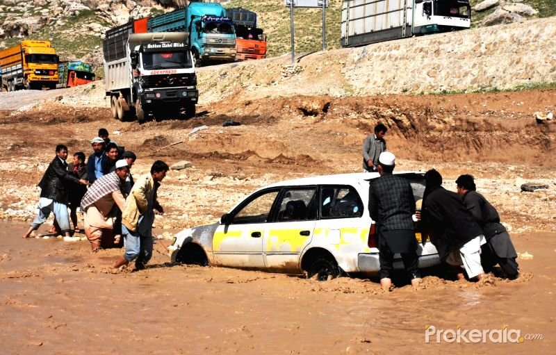 Afghan men push a car trapped in flood water after a heavy rain in Samangan province, northern Afghanistan, April 17, 2016.