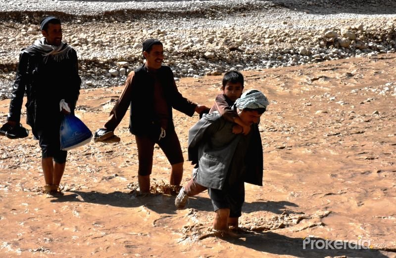 Afghan men wade through flood water after a heavy rain in Samangan province, northern Afghanistan, April 17, 2016.