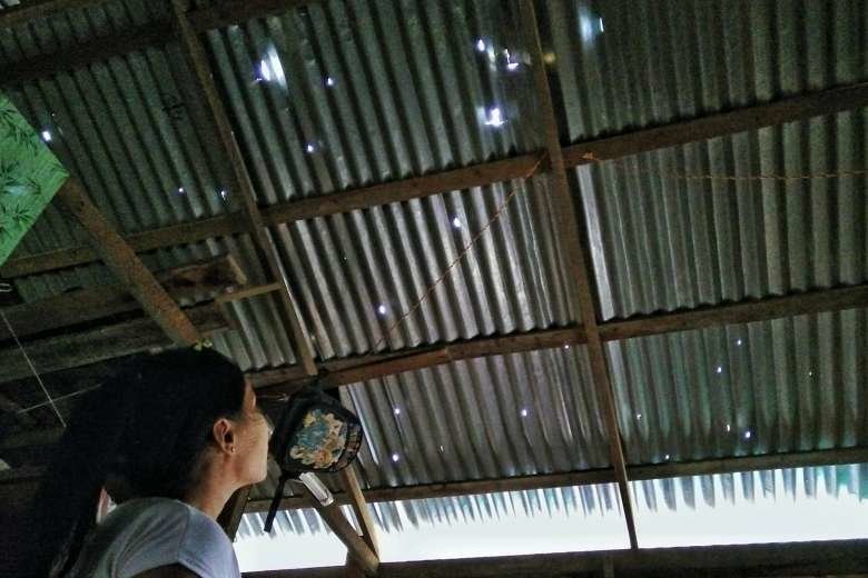 Click to enlarge A woman looking at the damage to a roof caused by hailstones in Mandalay on April 24, 2016.