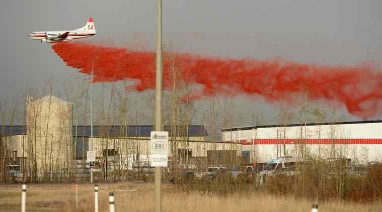 Click to enlarge A plane drops fire retardant on a nearby wildfire in Fort McMurray, Alberta