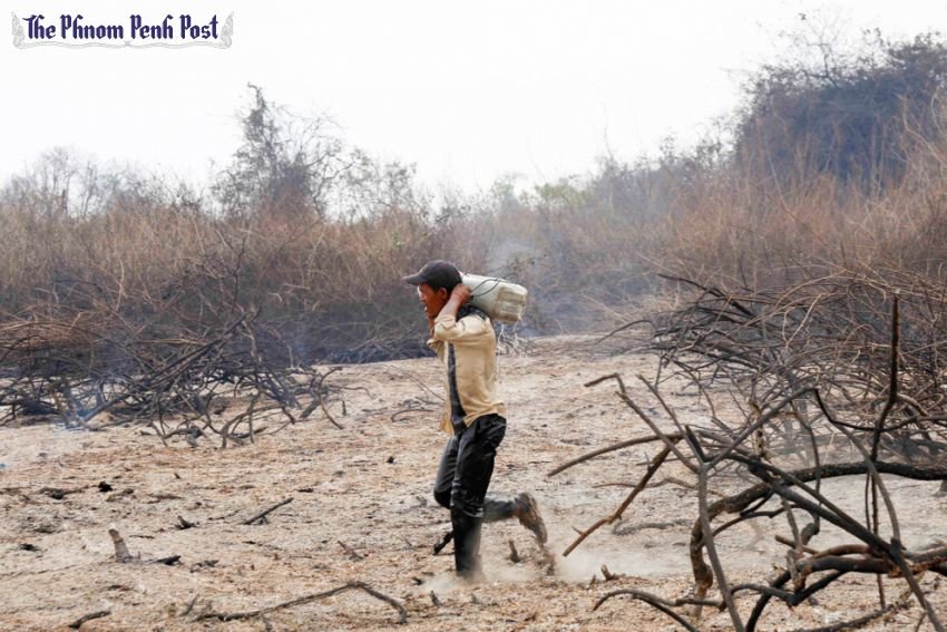 A man carries a container of water toward a fire in Battambang’s Prek Toal village earlier this week in a desperate effort to control the blaze. 