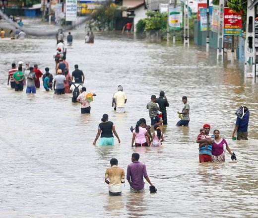  People walk through a flooded road after they moved out from their houses in Biyagama, Sri Lanka. 
