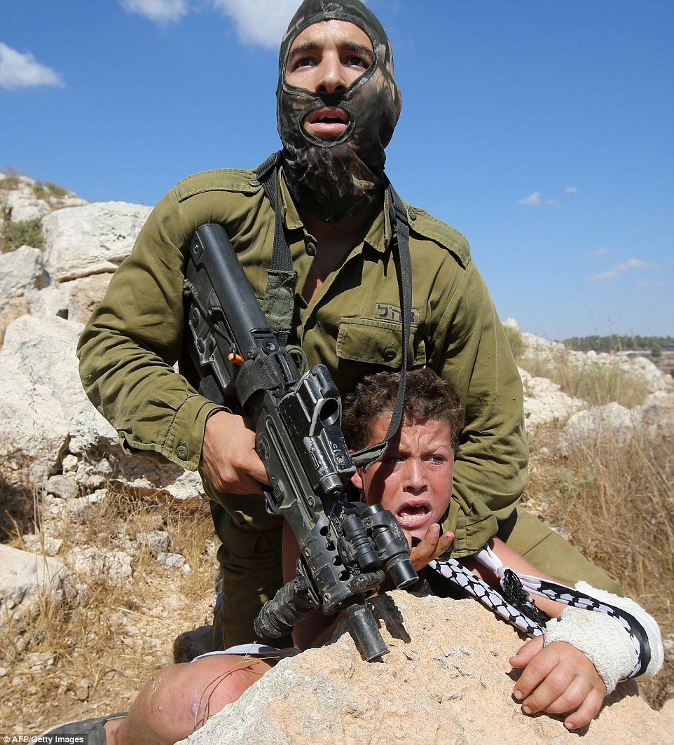 Israeli soldier chokeholds young boy at gunpoint