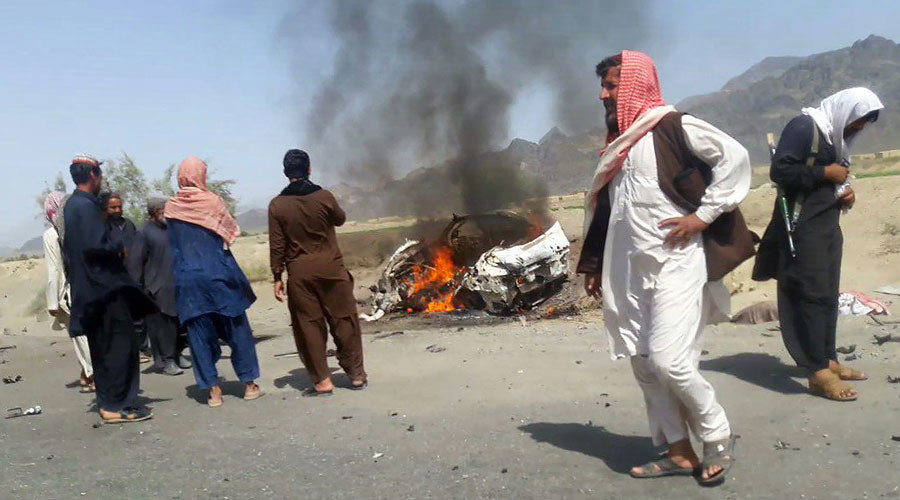 Pakistani local residents gathering around a destroyed vehicle hit by a drone strike in which Afghan Taliban Chief Mullah Akhtar Mansour was believed to be travelling in on May 21, 2016