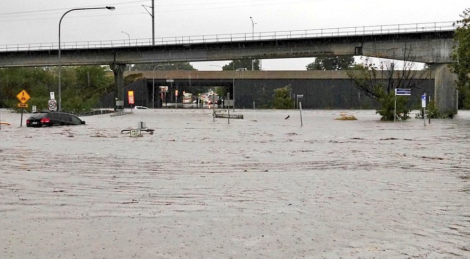 Two cars are pictured being swept down in the floods at Toombul shopping centre near Brisbane. Australia's east coast is being battered by gale-force winds, strong rains and floods