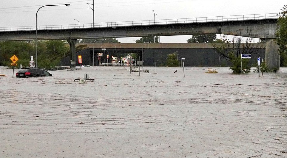 Click to enlarge Two cars are pictured being swept down in the floods at Toombul shopping centre near Brisbane. Australia's east coast is being battered by gale-force winds, strong rains and floods