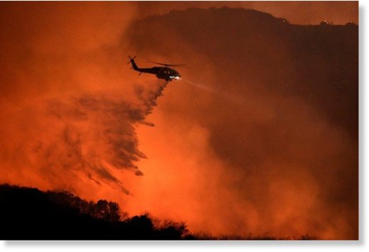  A helicopter makes a water drop on a fire in Calabasas, California.  