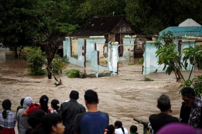 Click to enlarge People stand in front of a flooded area in Kampung Sewuresidential area in Solo, Central Java province, Indonesia, June 19, 2016.