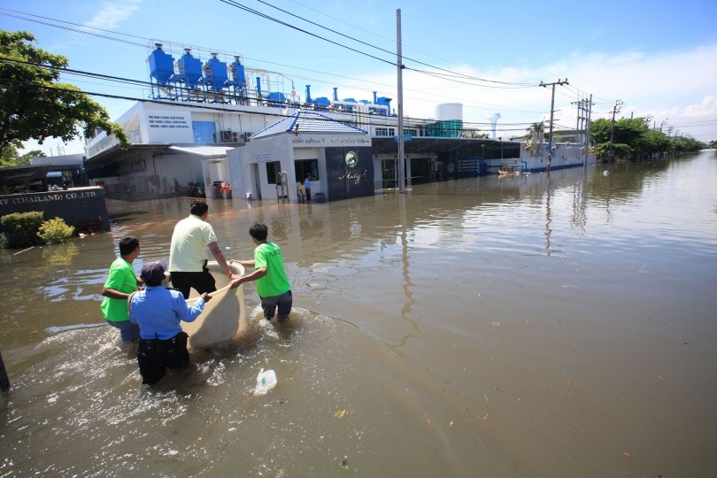 A factory worker in Bang Pu Industrial Estate in Samut Prakarn province is ferried to safety in a large bucket yesterday after the area is inundated in up to 60 centimetres of water.