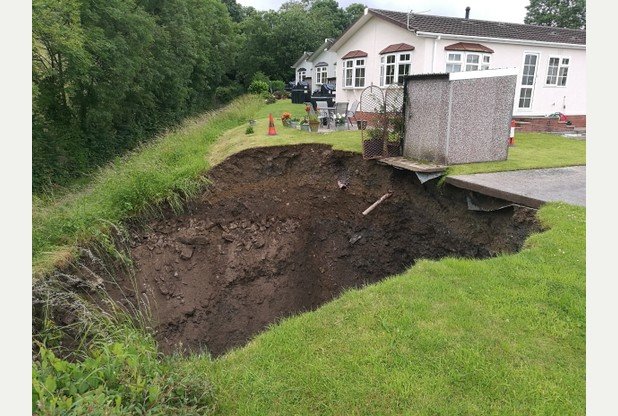 The 30 foot wide hole has left a storage shed dangling over the edge