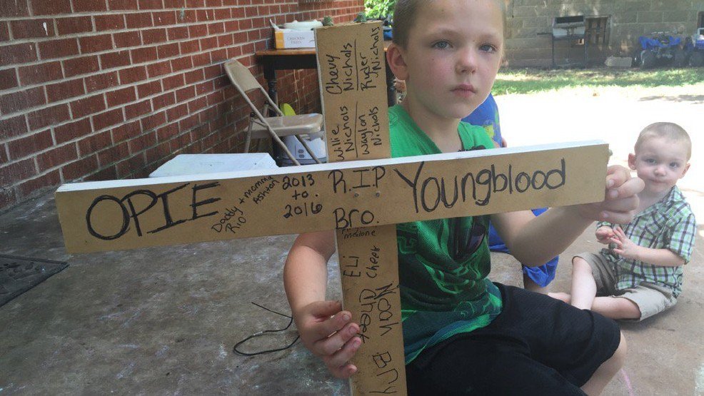 boy holds sign for dog opie