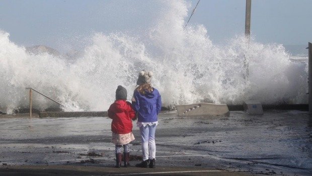 Children watch the rough seas along Steyne Avenue, near Plimmerton train station.
