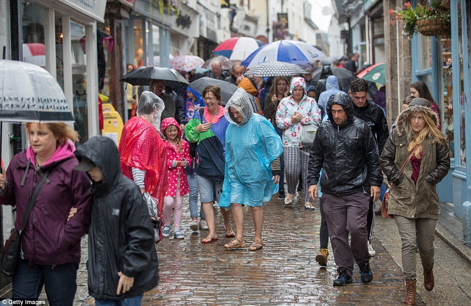 Click to enlarge Visitors and residents in St Ives scramble for cover from the rain (pictured) as 'Awful August' gets off to a wet start
