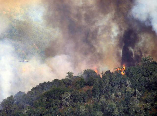 A helicopter flies over a back burn on a ridge south west of Cachagua as firefighters battle a wildfire in east Carmel Valley, Calif., Monday, Aug. 1, 2016. Higher humidity and lower temperatures on Monday helped firefighters battle the destructive wildfi