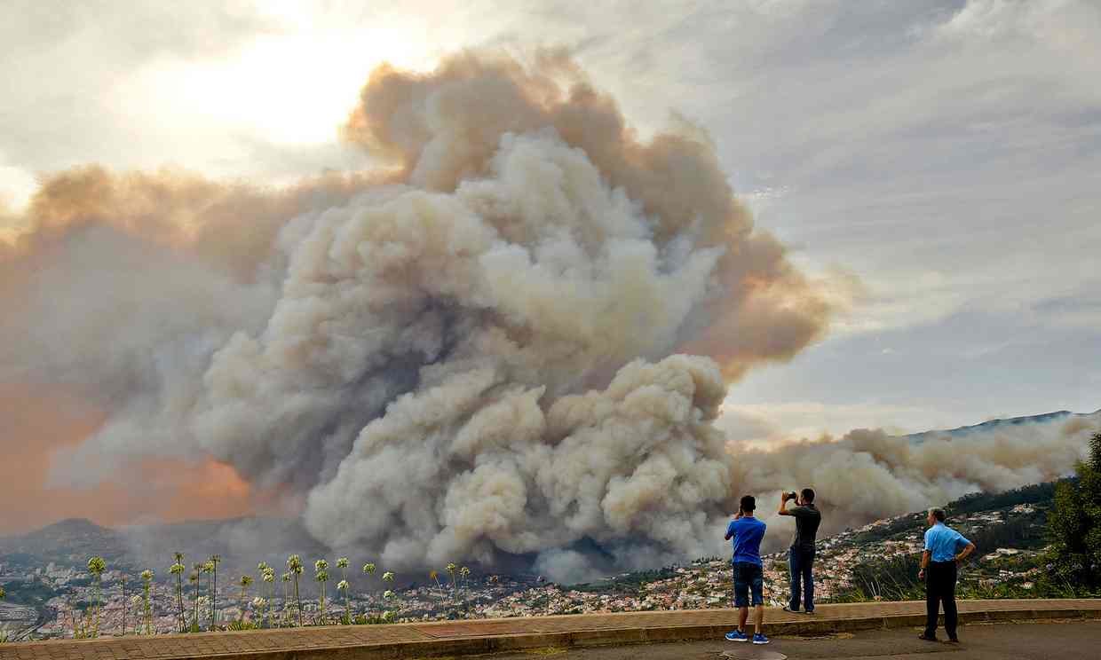 People take pictures of the smoke rising from a wildfire at Curral dos Romeiros in Funchal.  