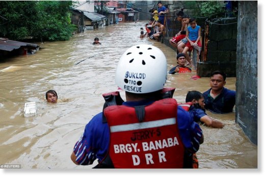 Rescuers (pictured) are seen rowing through the flooded streets trying to evacuate residents who can be seen clinging to debris that has become lodged in the deep currents 