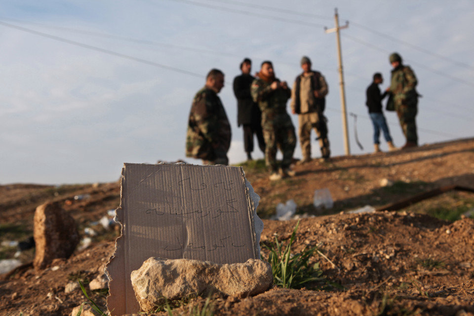 Click to enlarge Kurdish Peshmerga forces inspect a site marked in Kurdish with a sign reading ‘Kurdish mass grave’
