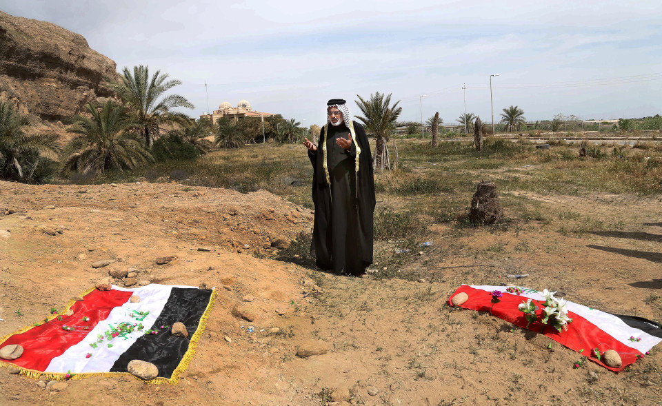 Click to enlarge A man prays for his slain relative at the site of a mass grave believed to contain bodies of Iraqi soldiers