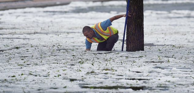 Much of eastbound Platte Ave. between Union Blvd. and Circle Dr. was shut down because of flooding and heavy hail after a storm Monday, Aug. 29, 2016, in Colorado Springs, Colo. Colorado Springs city worker Corey Rivera reaches into frigid water to find w