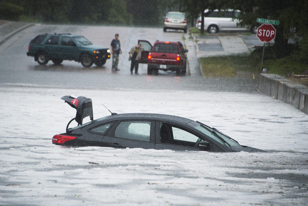 A half submerged abandoned car sits in a combination of hail and water on Tia Juana Street just north of Platte Avenue during a heavy thunderstorm Monday, Aug. 29, 2016, in Colorado Springs, Colo. The driver escaped without injury. 