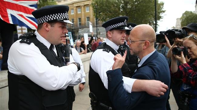 Police officers separate an anti-Brexit protester from pro-Brexit demonstrators