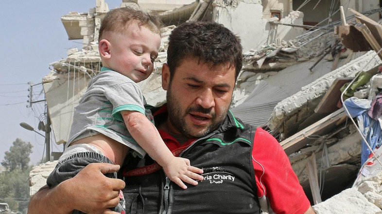 A Syrian man carries a baby