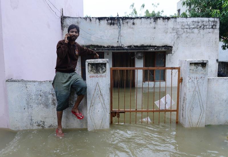 An Indian man speaks on his mobile phone outside his flooded home, following heavy rain in Nijampet a low lying area on the outskirts of Hyderabad on September 21, 2016.