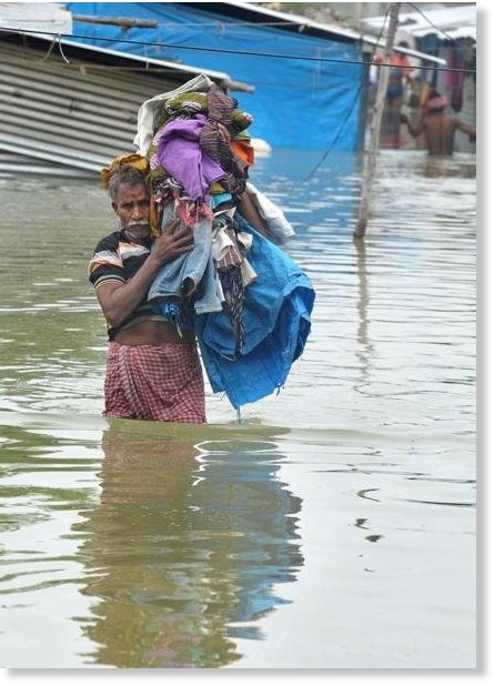 Man carries his belongings along a flooded street, following heavy rain in Nijampet, a low lying area on the outskirts of Hyderabad on September 21, 2016.